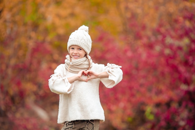 Adorable niña en el hermoso día de otoño al aire libre