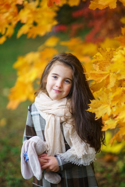 Adorable niña con hojas de otoño en el parque de belleza