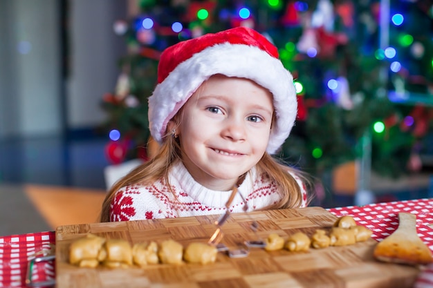 Adorable niña horneando galletas de jengibre para Navidad