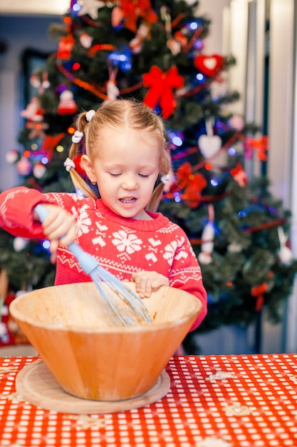 Adorable niña horneando galletas de jengibre de Navidad