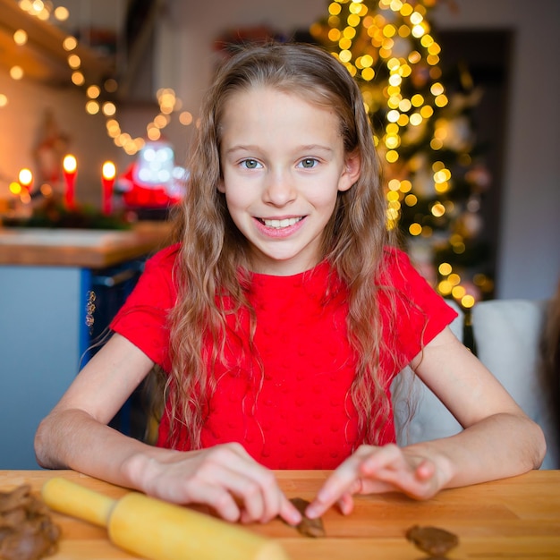 Adorable niña horneando galletas de jengibre navideñas