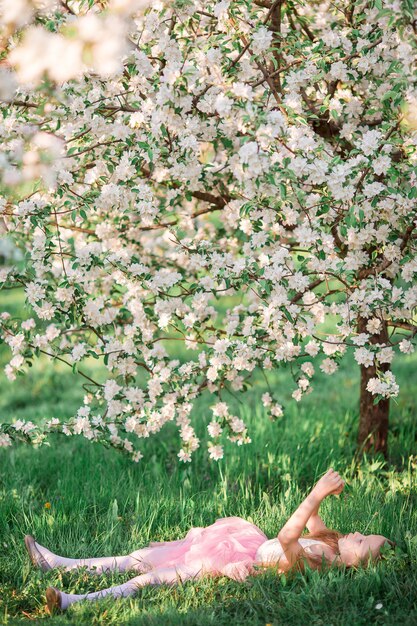 Adorable niña en jardín floreciente de cerezo en primavera