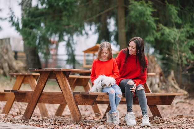 Adorable niña y joven madre con cachorro al aire libre