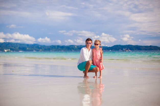 Adorable niña y joven papá en la playa de arena blanca