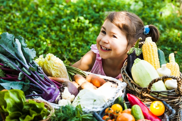 Adorable niña juega con una variedad de verduras en el césped