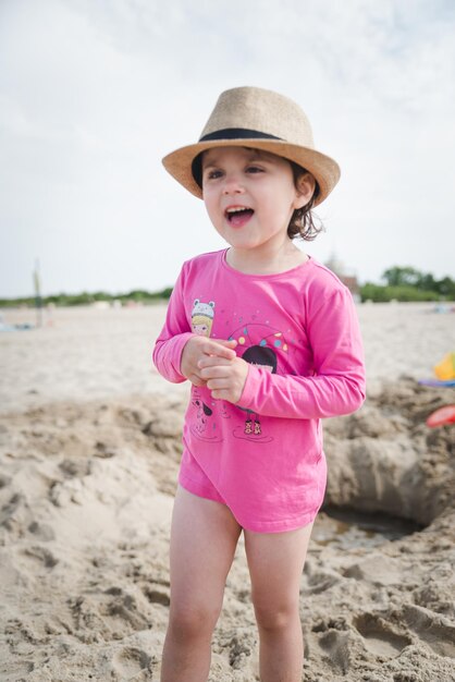 Adorable niña jugando con arena en el mar