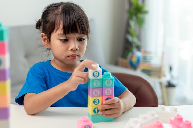 Adorable niña jugando bloques de juguete en una habitación luminosa