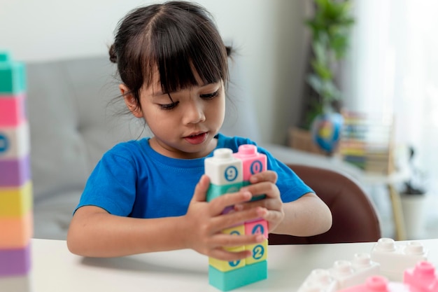 Adorable niña jugando bloques de juguete en una habitación luminosa