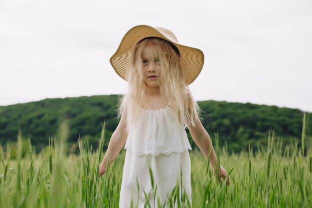 Adorable niña jugando en el campo de trigo en un cálido día de verano