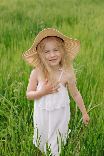 Adorable niña jugando en el campo de trigo en un cálido día de verano