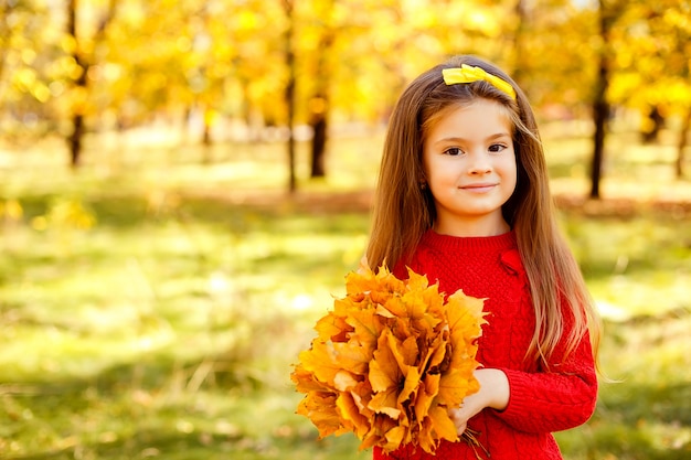 Adorable niña jugando con hojas de otoño