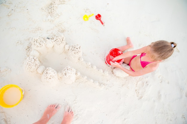 Adorable niña jugando con juguetes de playa durante vacaciones tropicales