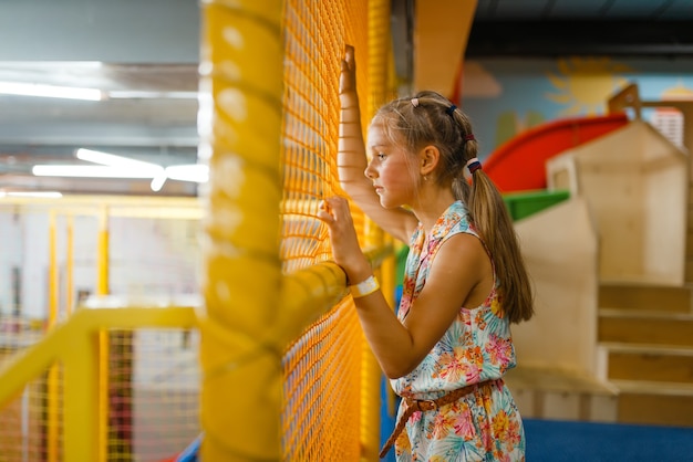 Adorable niña jugando en el laberinto de los niños, parque infantil en el centro de entretenimiento.