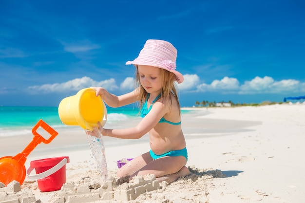 Adorable niña jugando en la playa con arena blanca