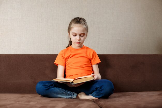 Adorable niña leyendo un libro en su casa