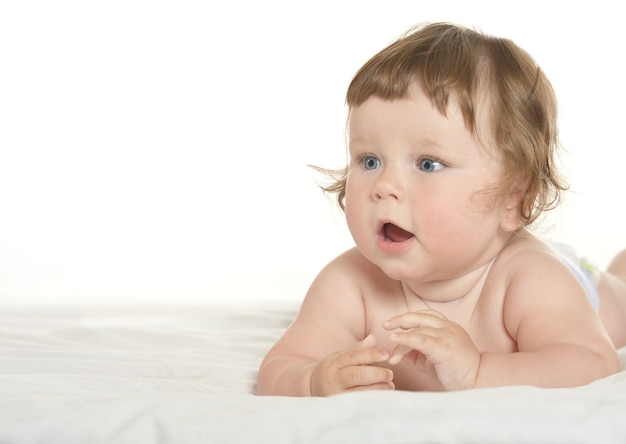 Adorable niña en una manta sobre un fondo blanco.