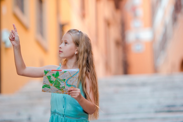 Adorable niña con mapa turístico en las calles romanas de Italia. Niño feliz toodler disfrutar vacaciones de vacaciones italianas en Europa.