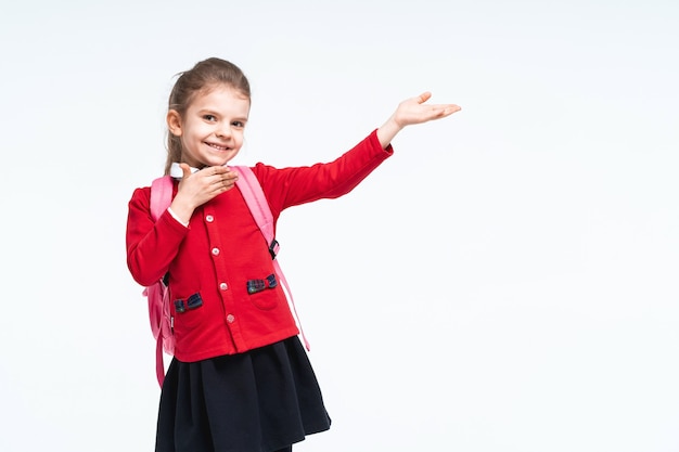 Adorable niña en mochila de vestido negro de chaqueta roja de la escuela