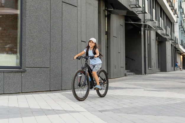 Adorable niña montando en bicicleta en una ciudad