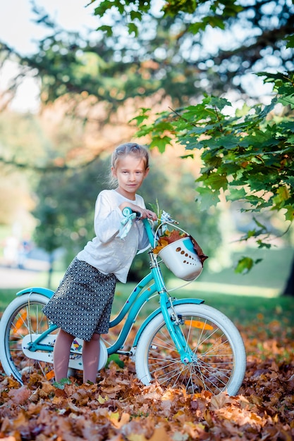 Adorable niña montando una bicicleta en el hermoso día de otoño