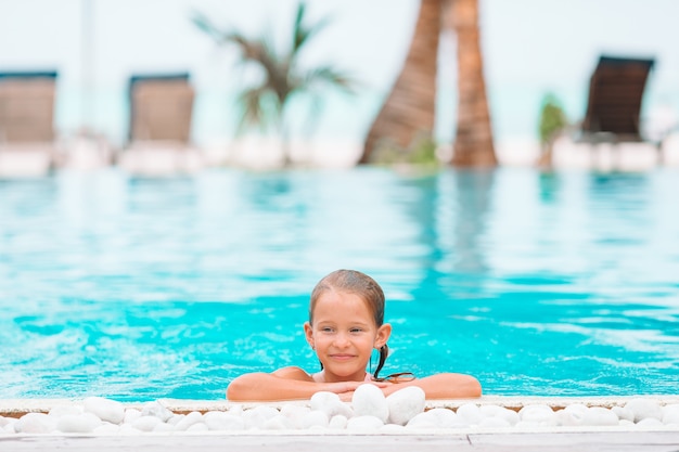 Adorable niña nadando en la piscina al aire libre