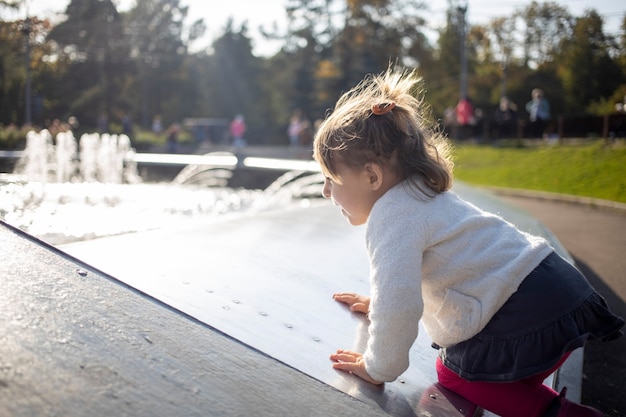 Adorable niña pequeña juega en un día soleado en el parque de cerca