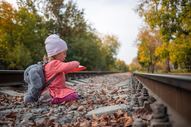 Adorable niña pequeña jugando con una pala en los rieles