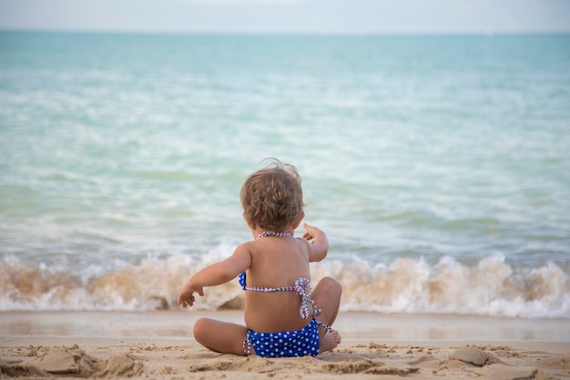 Adorable niña pequeña jugando en la playa de arena de la isla tropical