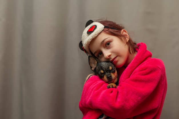 Adorable niña con perrito chihuahua de pie y mirando hacia arriba. chica sosteniendo perros chihuahua en sus brazos. niña de 9 años con una mascota en casa en sus brazos. El concepto de amor por los animales. Hogar