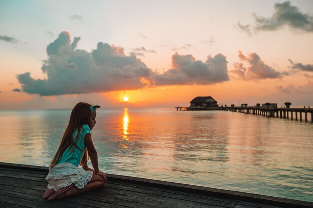 Foto adorable niña en la playa al atardecer