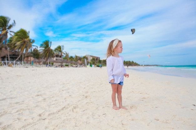 Adorable niña en la playa blanca del Caribe en un día soleado