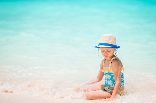 Adorable niña en la playa en sus vacaciones de verano