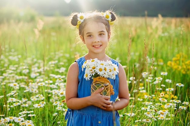 Adorable niña con un ramo de margaritas en un campo con margaritas en un día soleado