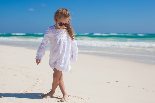 Adorable niña en ropa hermosa bailando en la playa tropical