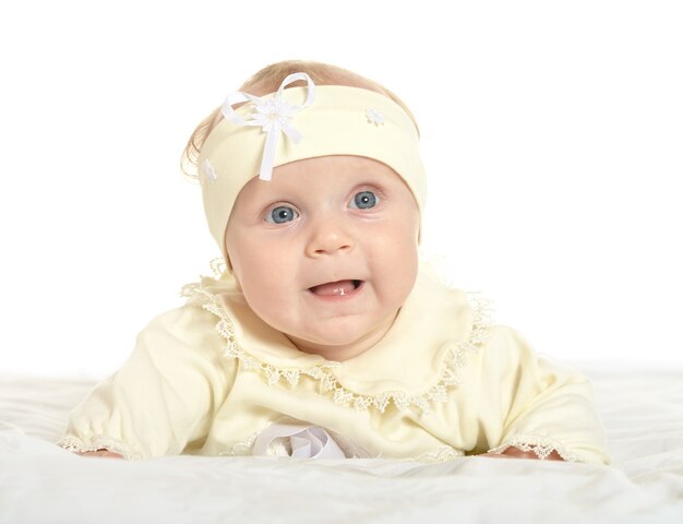 Adorable niña en ropa linda en una manta sobre un fondo blanco.