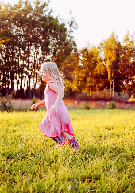 Adorable niña rubia en un prado en un día soleado de verano