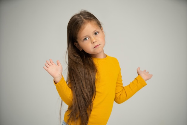 Adorable niña de seis años aislada en blanco bastante castaño niño europeo pose interior sonriendo mirar a la cámara