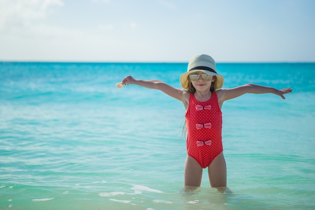 Adorable niña con sombrero en la playa durante las vacaciones de verano