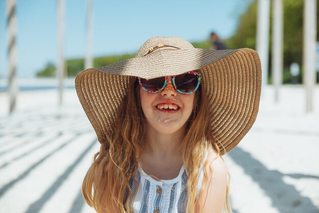 Adorable niña con sombrero en la playa en vacaciones de verano