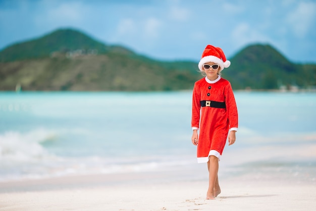 Adorable niña con sombrero de Santa en playa tropical