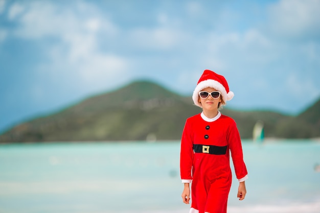 Adorable niña con sombrero de Santa en playa tropical