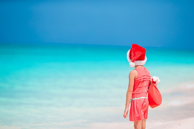 Adorable niña con sombrero de Santa en playa tropical