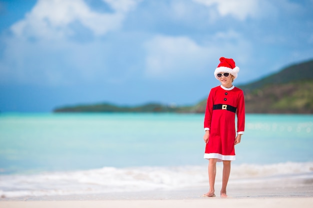 Adorable niña con sombrero de Santa en playa tropical