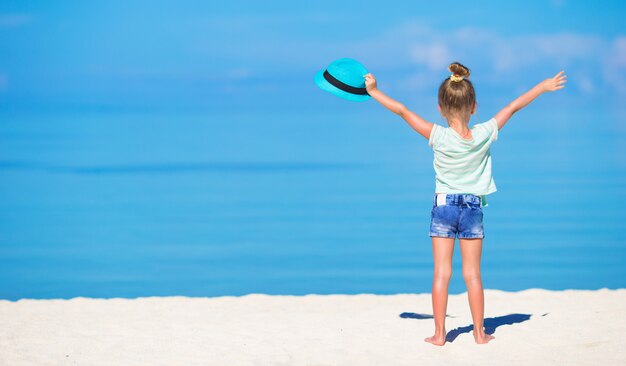 Adorable niña sonriente feliz con sombrero en vacaciones en la playa