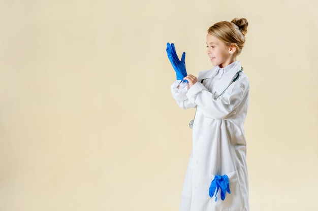 Adorable niña sonriente vestida como un médico con estetoscopio aislado