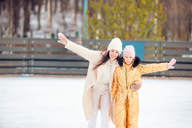 Adorable niña con su madre patinando en la pista de hielo