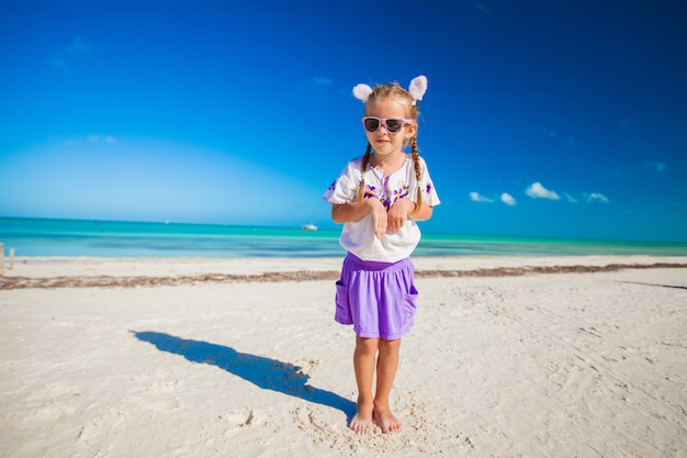 Adorable niña en traje de pascua en la exótica playa