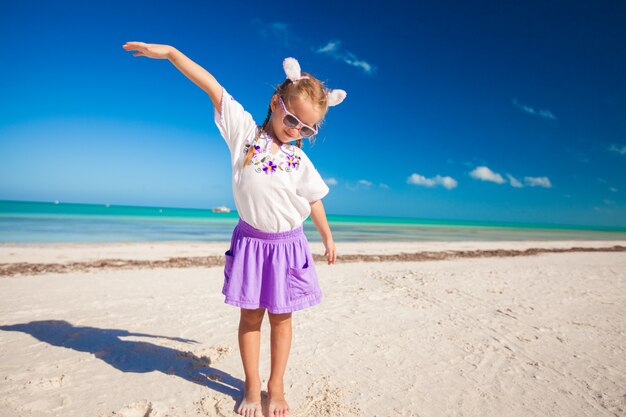 Adorable niña en traje de pascua en la exótica playa