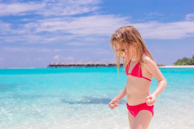 Adorable niña durante las vacaciones en la playa divirtiéndose