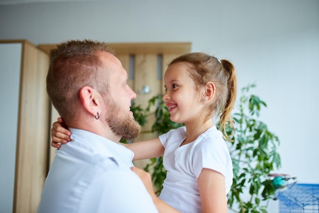 Adorable niña de vestido blanco abrazando amoroso padre